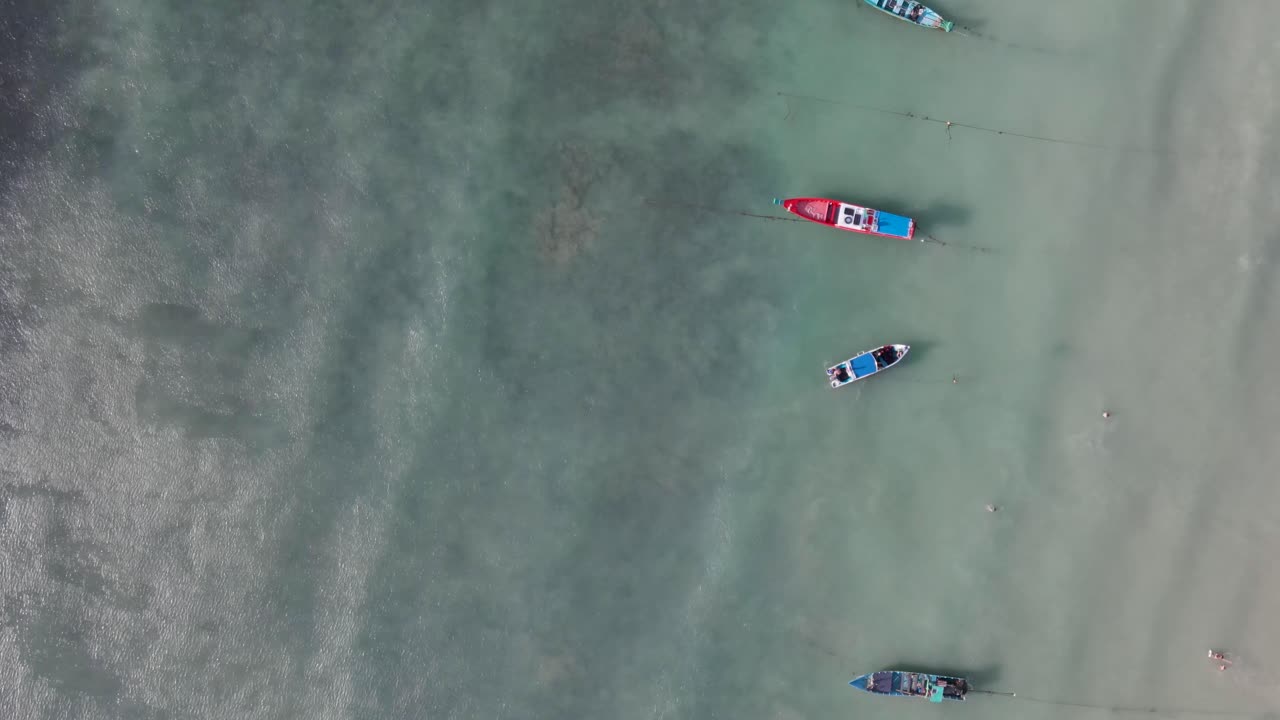 Aerial Birds Eye View Along Row Of Moored Empty Boats Off Sairee Beach In Shallow Waters