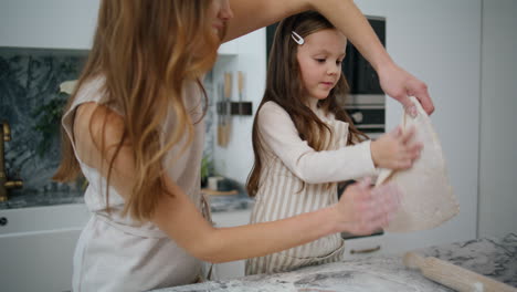 niño enfocado preparando pasteles con la madre en casa. madre positiva sosteniendo la masa