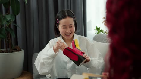 young asian woman in good mood eats noodles with wood sticks at home with her friend