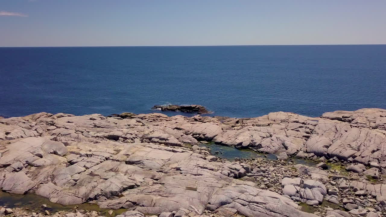 Beautiful flyover of a rocky, rugged shoreline along the Atlantic Coast in Nova Scotia, Canada on a bright, sunny day