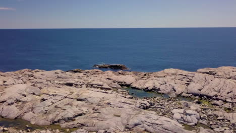 beautiful flyover of a rocky, rugged shoreline along the atlantic coast in nova scotia, canada on a bright, sunny day