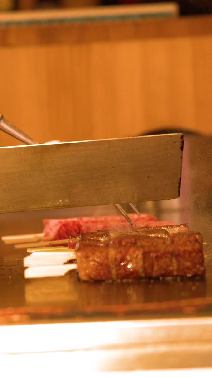 日本で、シェフが熱い鉄板焼きグリルで高級和牛ステーキを巧みに調理している。