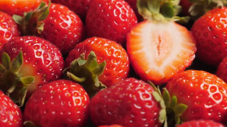una gran cantidad de fresas rojas y maduras girando, en primer plano