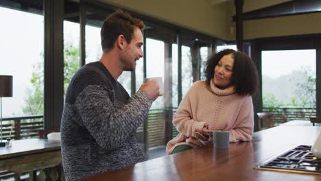 Happy-diverse-couple-talking-and-drinking-coffee-in-kitchen