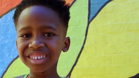 front view of happy african american schoolboy standing against wall in school 4k