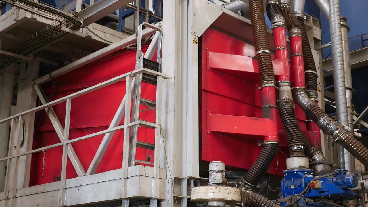 Piano statico di una potente macchina di lavorazione industriale con grandi porte rosse e complesse tubazioni corrugate in un impianto di riciclaggio pneumatici