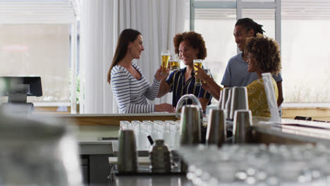 diverse group of happy friends raising glasses making a toast at a bar