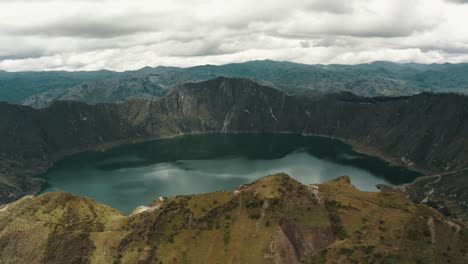 aerial panorama view showing volcano landscape with calm blue colored crater lake in andes