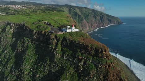 el retiro de drones establece la costa escarpada de madeira, portugal, con un faro en un punto panorámico.