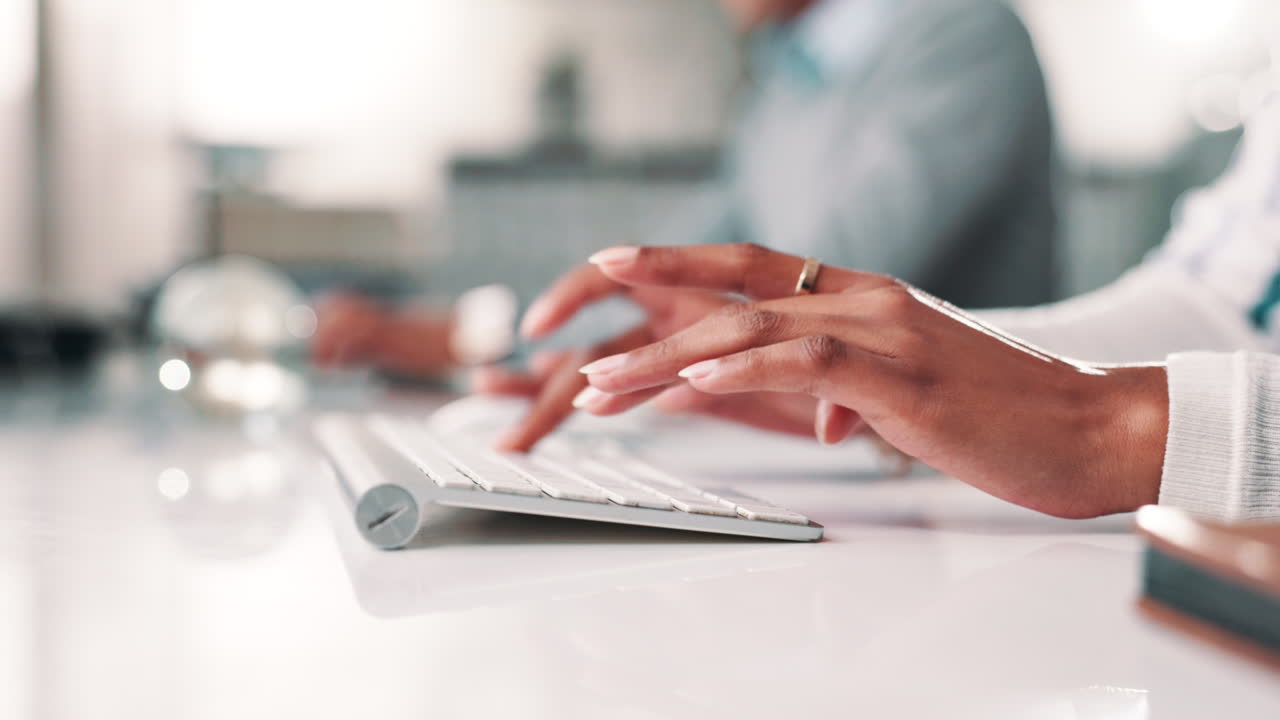 Hands typing on a keyboard in an office