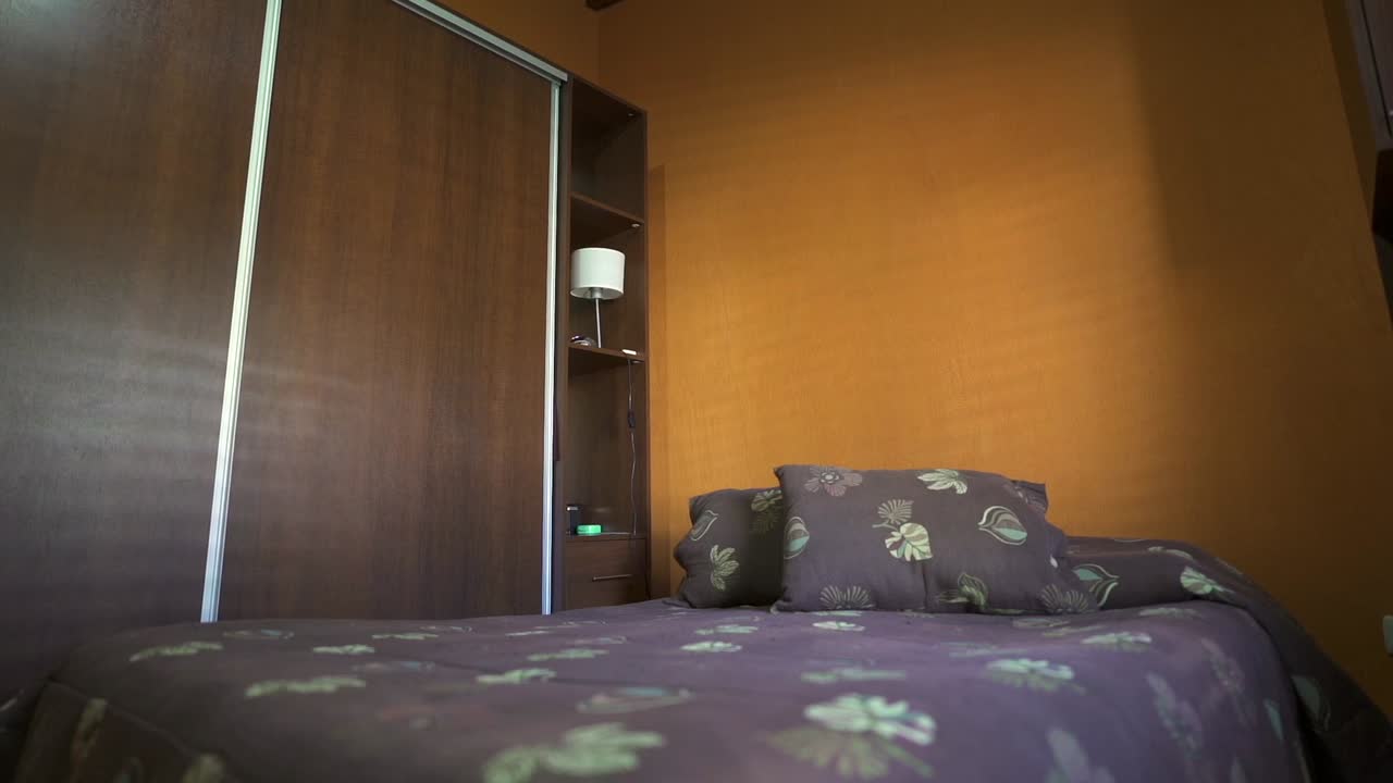 Slow pan reveals bold-colored Airbnb house bedroom featuring cozy bed and minimalist storage. Ideal for vacation rental showcases.