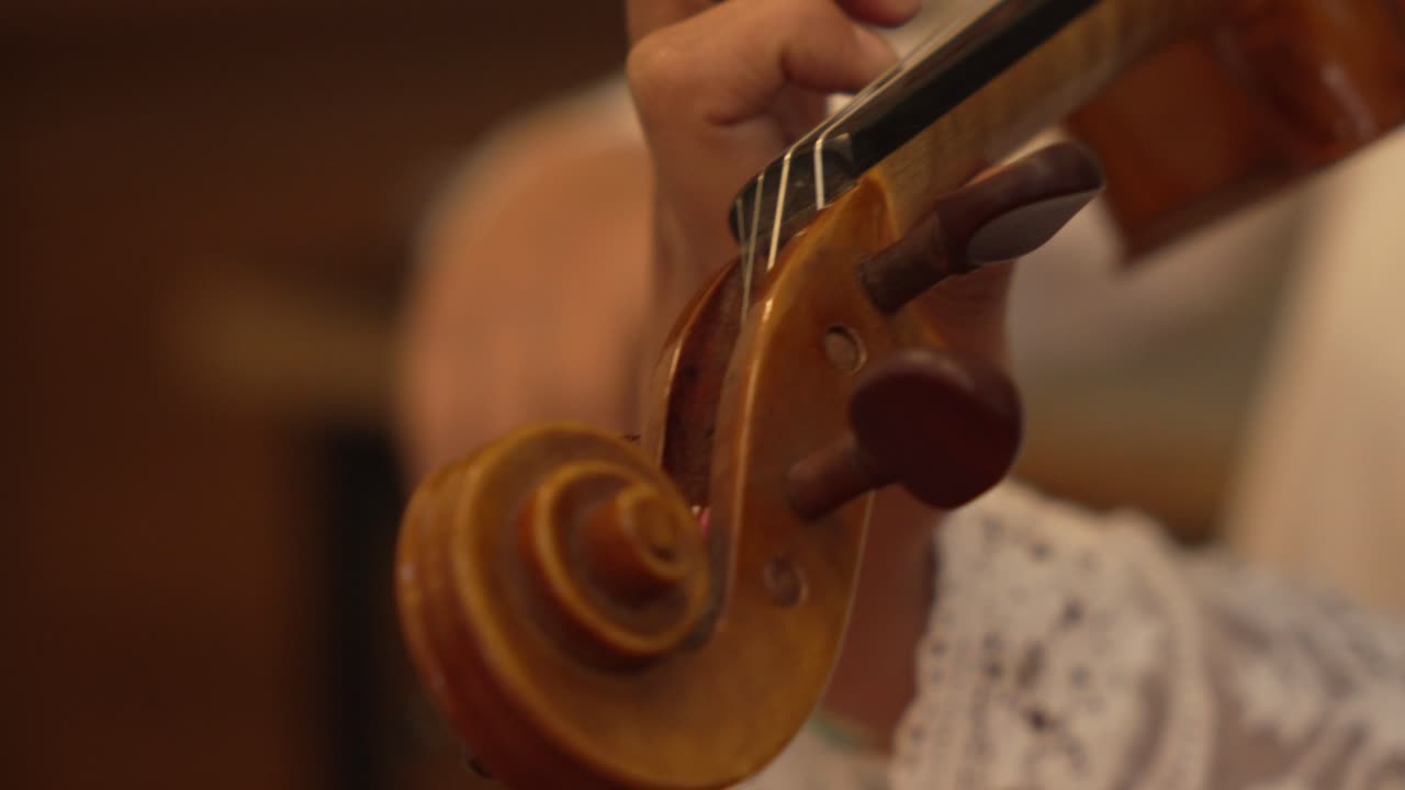 Close-Up of Violin Peg with Musician's Bow Performance in a Studio Setting