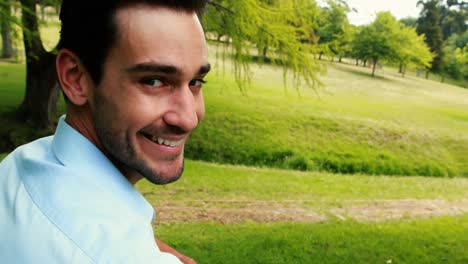 Smiling-man-sitting-on-bench-in-park