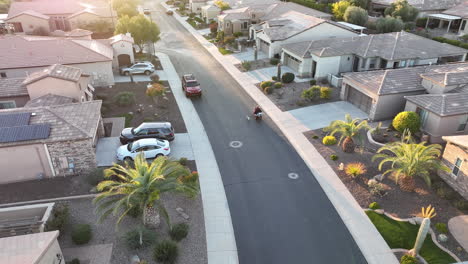 Drone-shot-of-someone-using-a-motorized-wheelchair-to-walk-their-dog-under-the-suburban-setting-sun