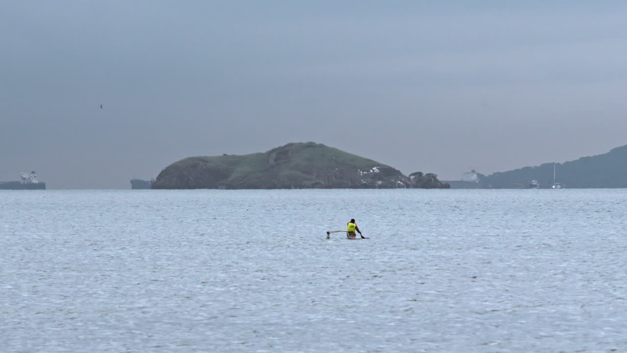 Static shot of a local man canoeing around the Veracruz Beach shoreline