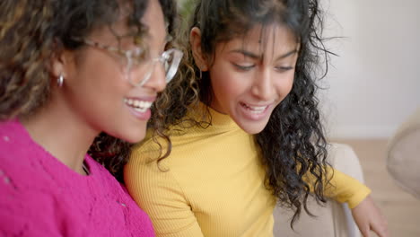 Happy-diverse-female-teenage-friends-sitting-and-embracing-at-home,-slow-motion