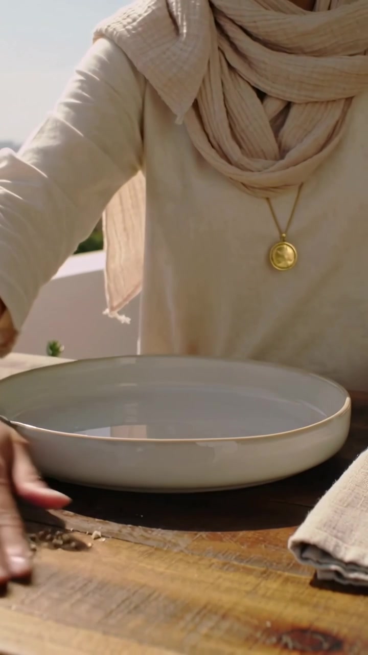 Video verticale: Posizionamento della biancheria, donna con top color cuoio che riveste una ciotola sul tetto sollevando il panno e piegandolo a destra.