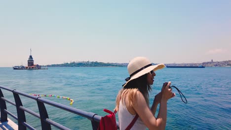 beautiful girl takes pictures of bosphorus and maidens tower in uskudar town,istanbul,turkey