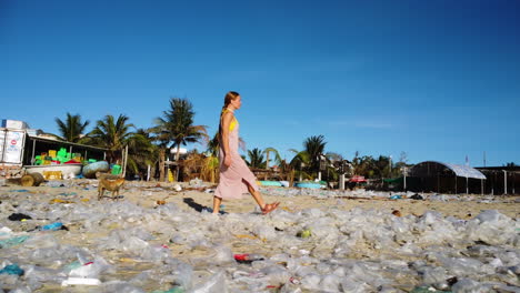 caucasian woman walking in sandals on polluted beach with plastic bag waste, toxic garbage, ocean pollution concept, global warming