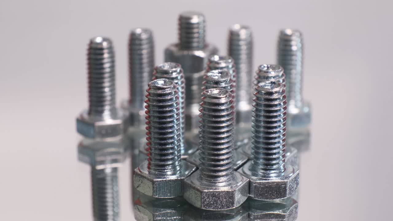 grupo giratorio de tornillos metálicos galvanizados de primer plano. pernos de acero inoxidable aislados en el fondo reflectante del espejo.