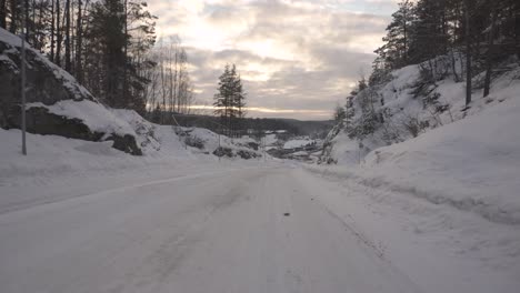 winter landscape - dirt road in the forest covered in snow during sunset - aerial low