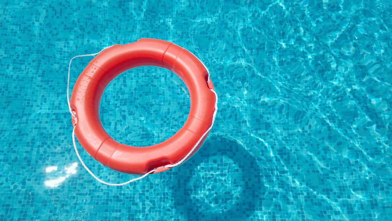 Life Belt or Life Preserver Floating on Top of Sunny Blue Water, slow motion