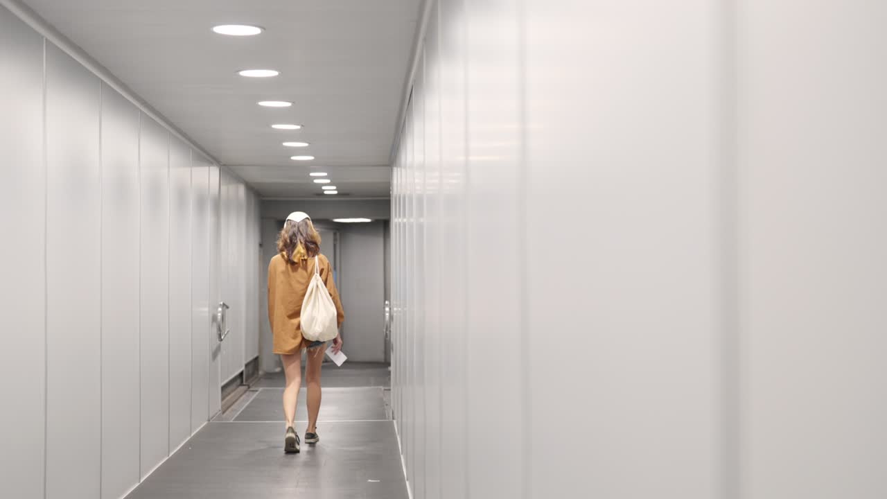 молодая азиатка проходит через проход аэропорта к самолету.