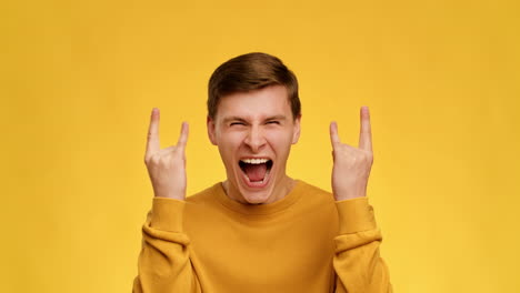 excited young man making rock gesture