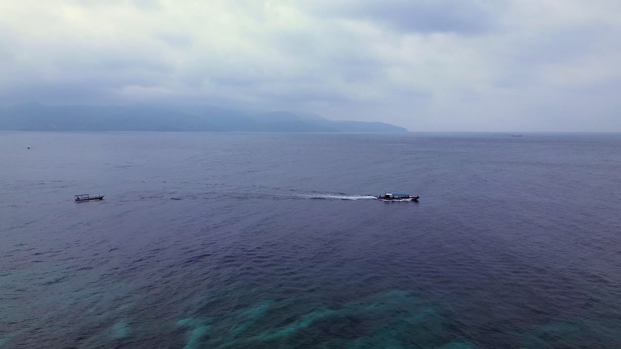 Aerial static camera view of calm sea under cloudy sky in the Gili Islands, ideal for serene travel content