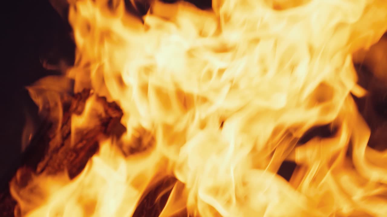 Falò che brucia di notte. Fiamme di fuoco su sfondo nero al rallentatore.