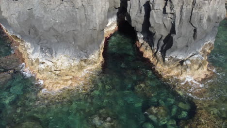 rocky cliffs on which the waves of clear blue turquoise sea water splash, canary island, hierro - drone shot