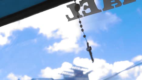 Close up slow motion shot of a crucifix pendant swinging in a tuk tuk in the Philippines. The Christian cross necklace swings as the taxi drives through a small town