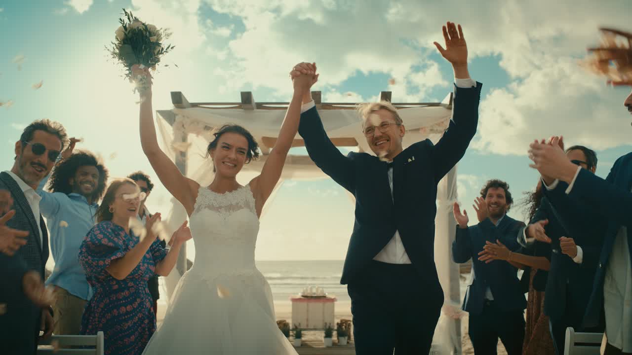 아름다운 신랑과 신부는 바다 근처의 해변에서 야외에서 결혼식을 축하합니다. 신혼부부에게 꽃잎을 던지는 최고의 다민족 다양한 친구들과 함께 완벽한 결혼 장소.