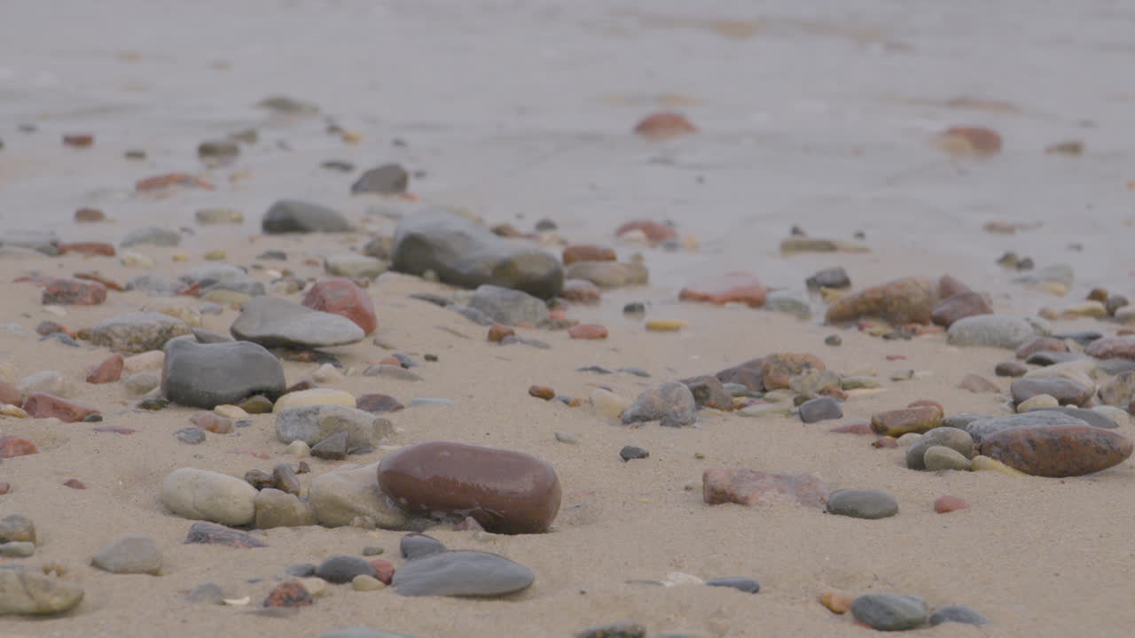 다양한 크기의 돌들이 모래 해변을 따라 어져 있습니다.