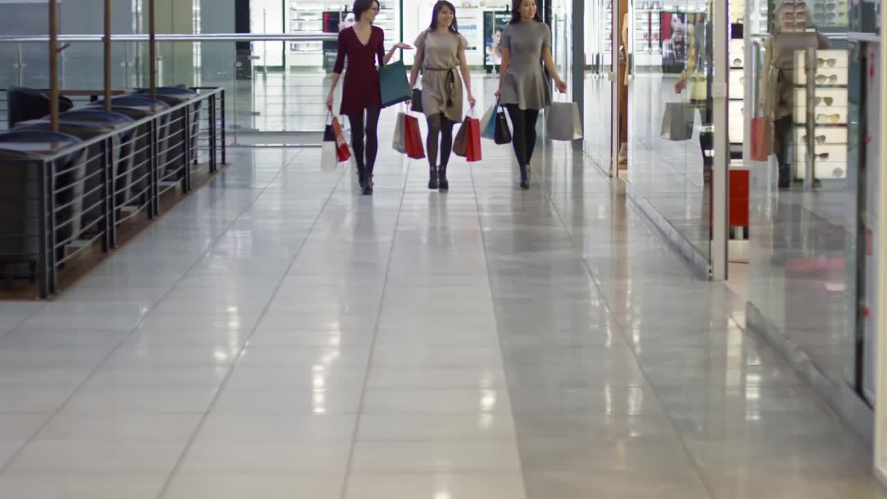 행복 한 고객 들 이 쇼핑 센터 에서 걸어가고 있다