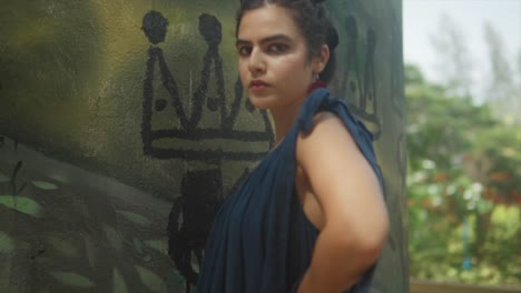 una chica con bollos peinados mira a la cámara con una expresión neutral mientras posa en un vestido azul