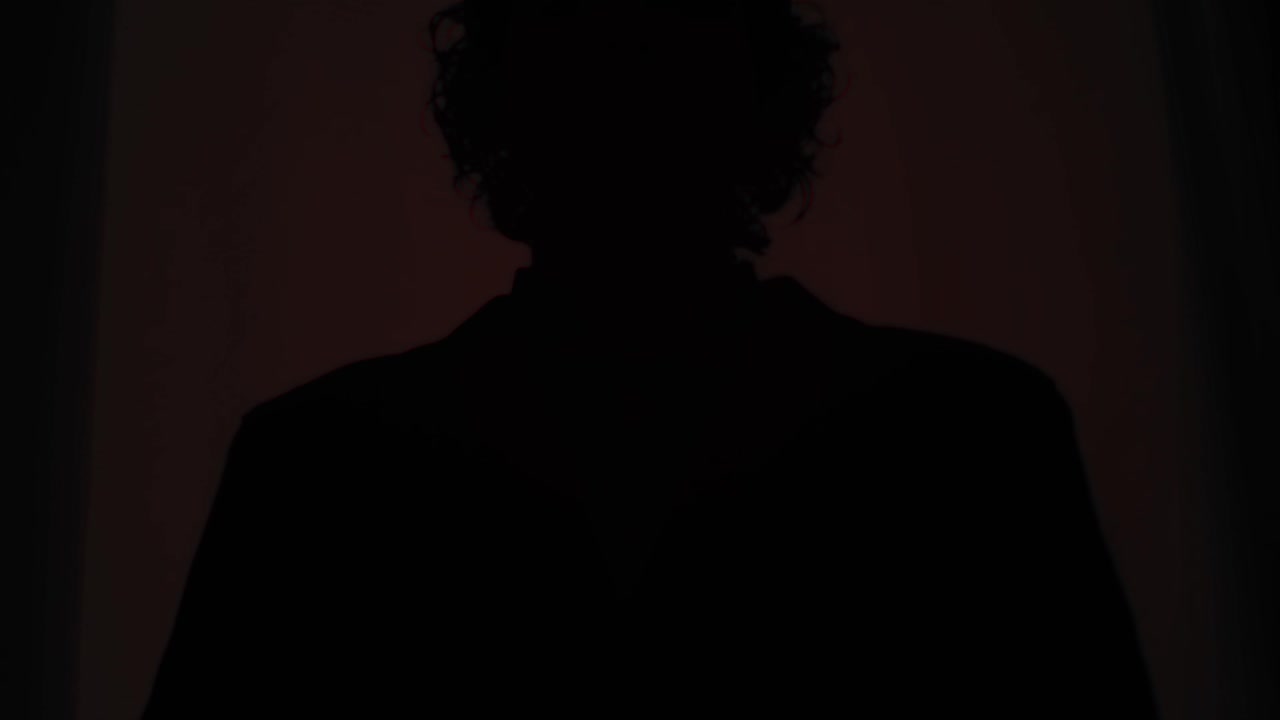 Silhouetted man in red flashing light emergency alert scene, tense cinematic atmosphere