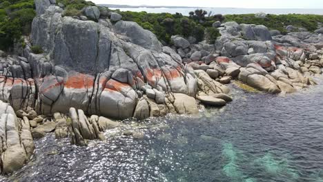 drone aerial over red bay of fires rocks and clear tropical water in tasmania slow motion 60fps