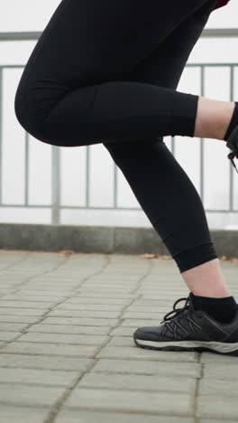 leg view of lady in black sneakers and black leggings jogging on urban pathway in morning light with dynamic motion capturing side fitness routine movement focus strength stride visible