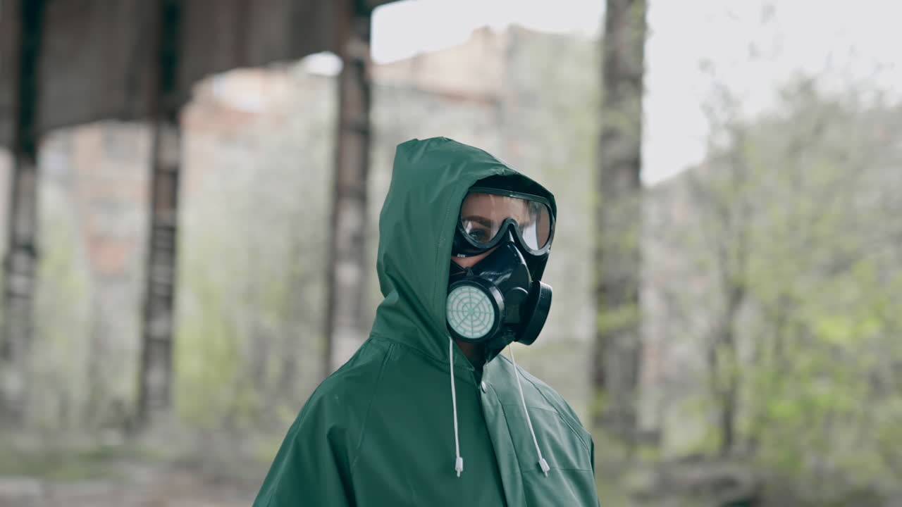 Person in chemical protective suit standing in distracted place. Survivor in abandoned place with piles of garbage from ruined buildings. Apocalypse concept