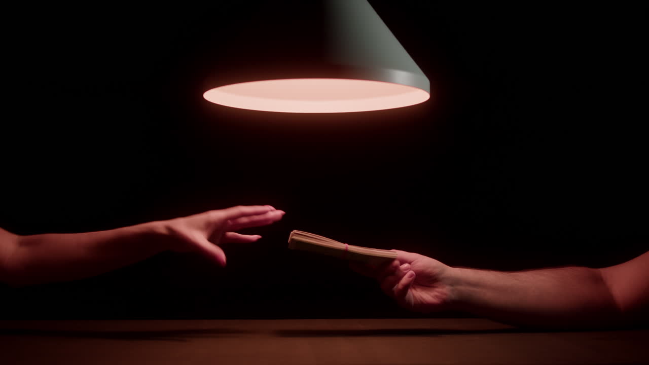 Hände tauschen einen Geldstapel unter einer schwachen Lampe aus