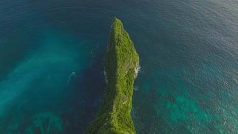 lush green sekartaji cliff surrounded by turquoise and blue sea water, aerial