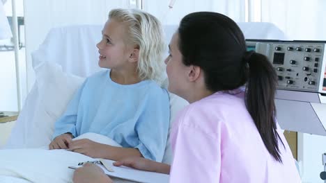 una niña recuperándose en el hospital hablando con una enfermera