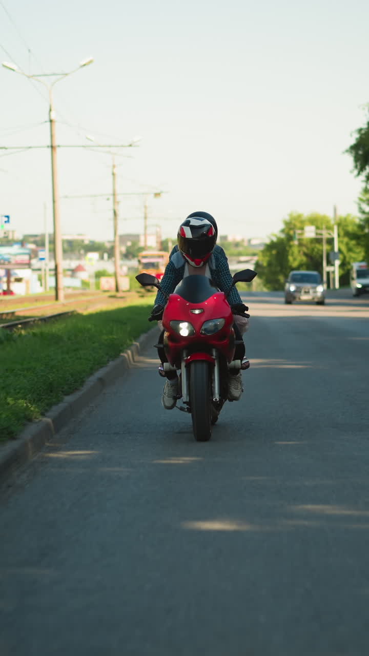 dos damas montan una bicicleta eléctrica con cascos, viajando cerca de las vías del ferrocarril con postes eléctricos y señales en el fondo