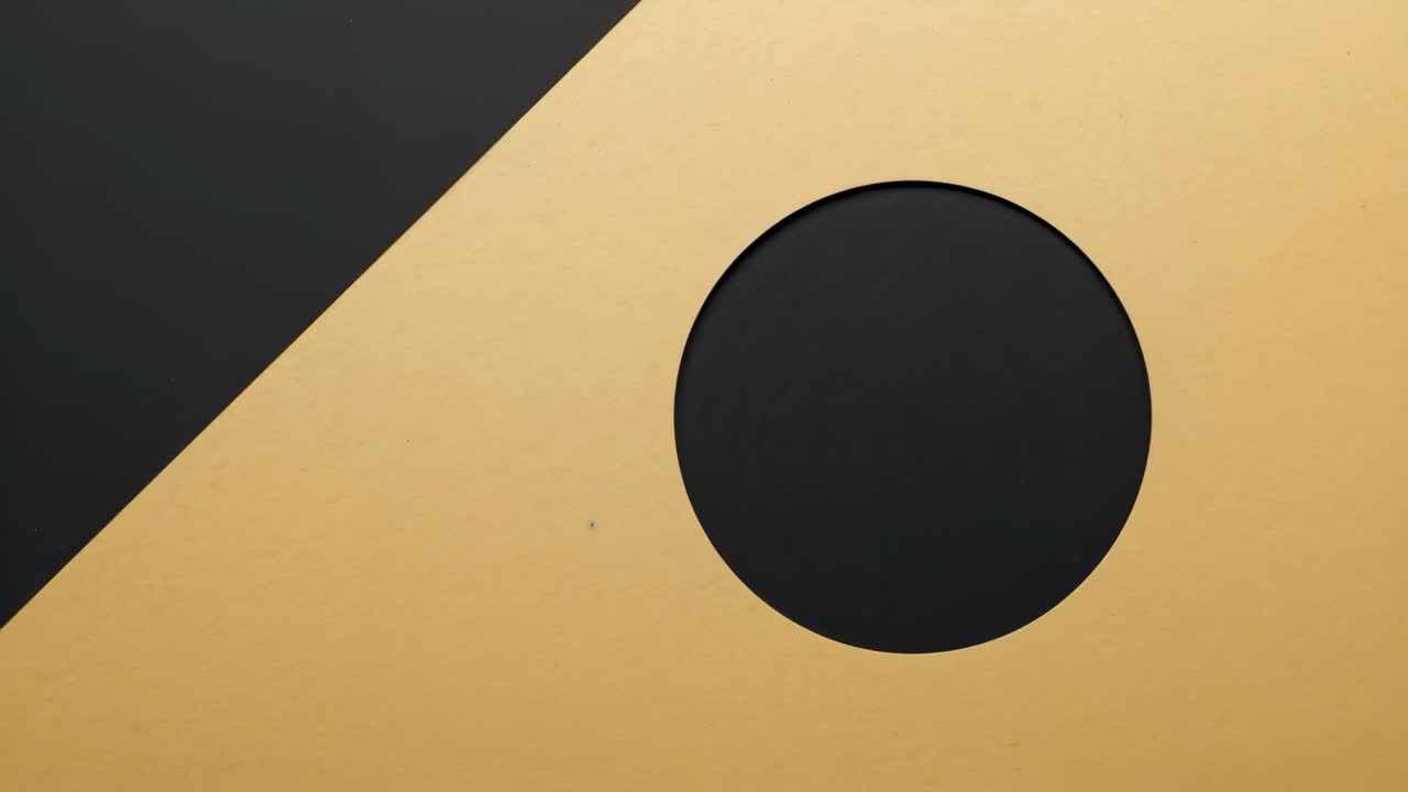 Frame prompt circular aperture sliding down gold plane showing dark diagonal at studio, copy space