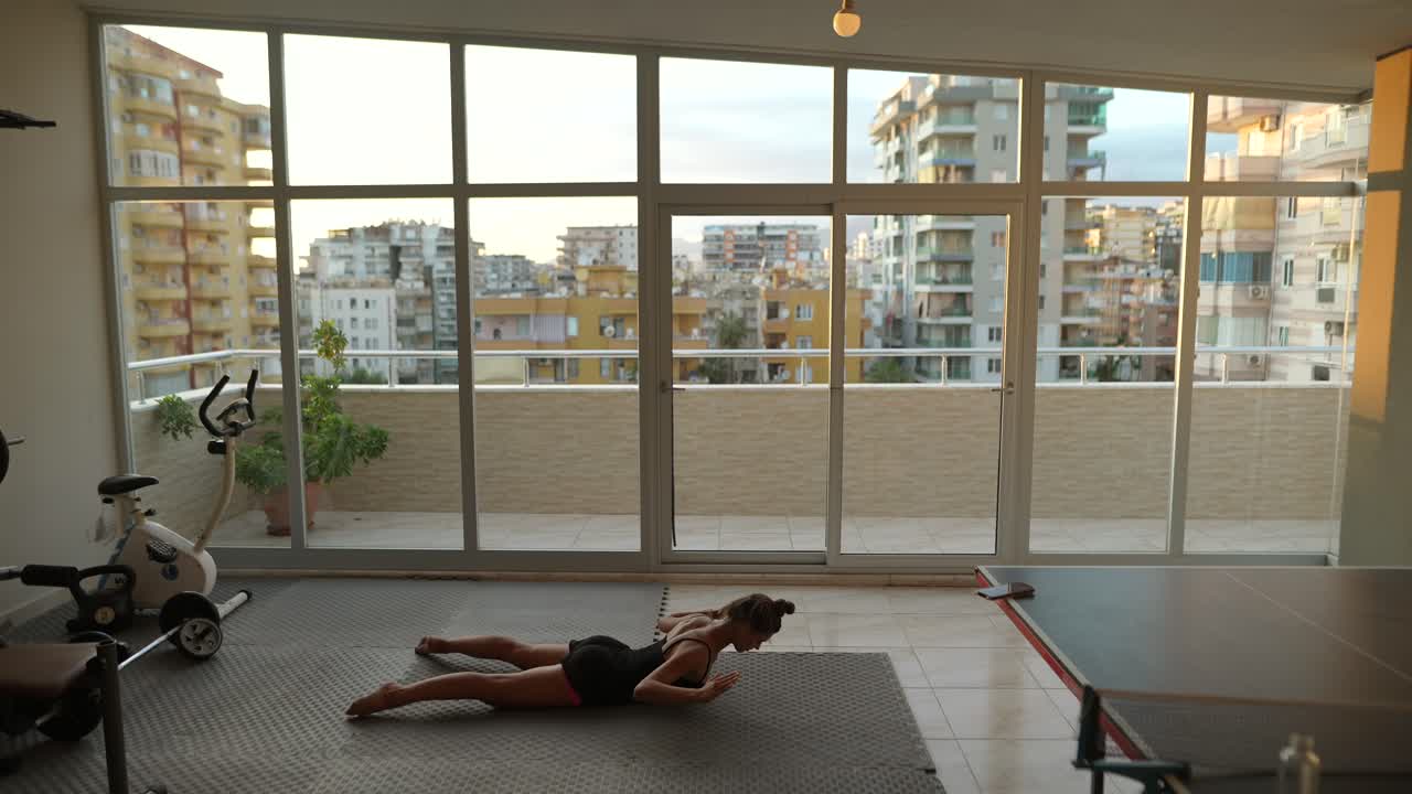 mujer haciendo yoga en un gimnasio casero con vista a la ciudad