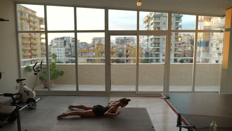 mujer haciendo yoga en un gimnasio casero con vista a la ciudad