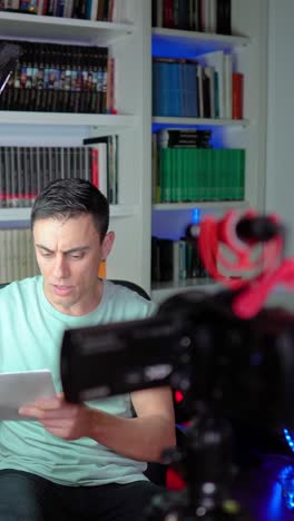 man recording video in front of bookshelf