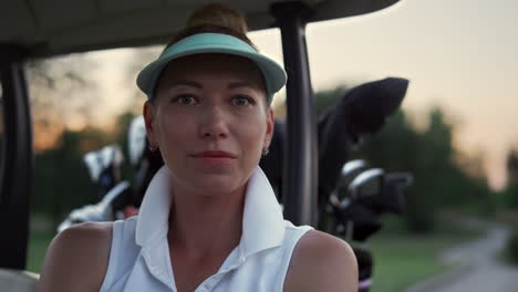 smiling golf player relax sitting at golf cart buggy on summer sunset course.