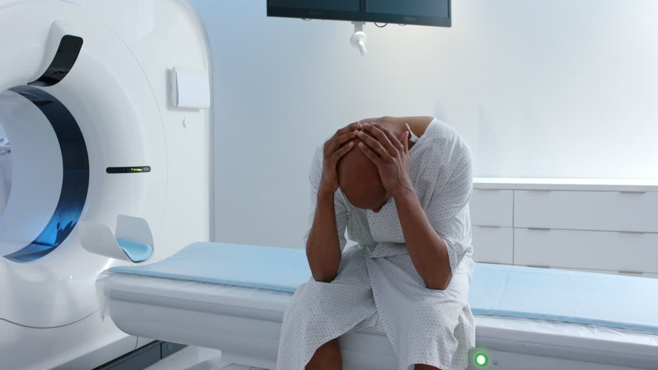 Un paziente sta reagendo all'attivazione della luce verde del gantry, afferrandosi il viso e irrigidendosi sul lettino d'esame.